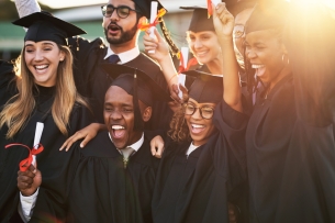 A group of students in graduation caps and gowns cheers. 